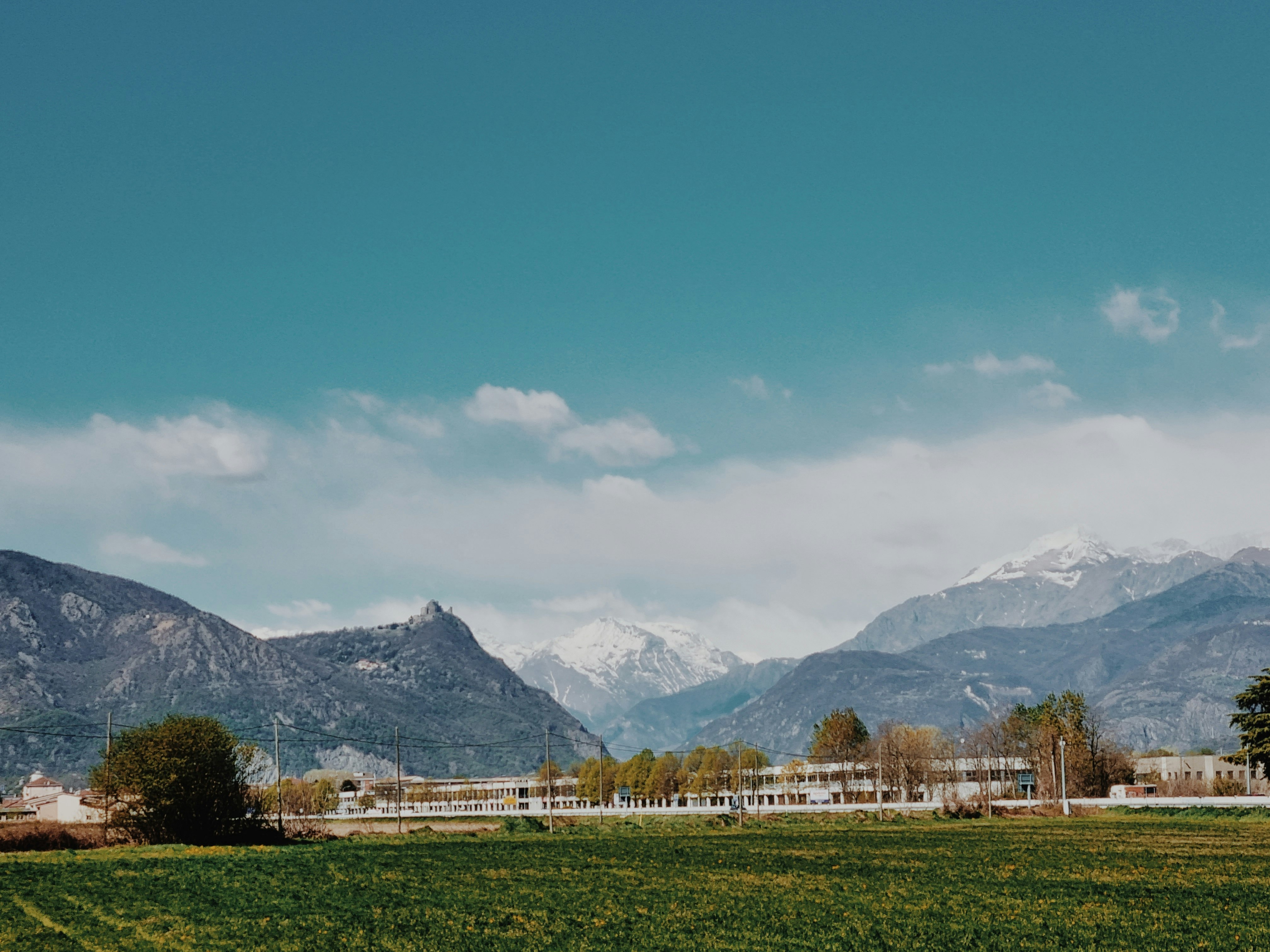 green grass field near mountains under blue sky during daytime